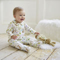 Baby wearing Meadow Print Jumpsuit sitting on a wooden floor