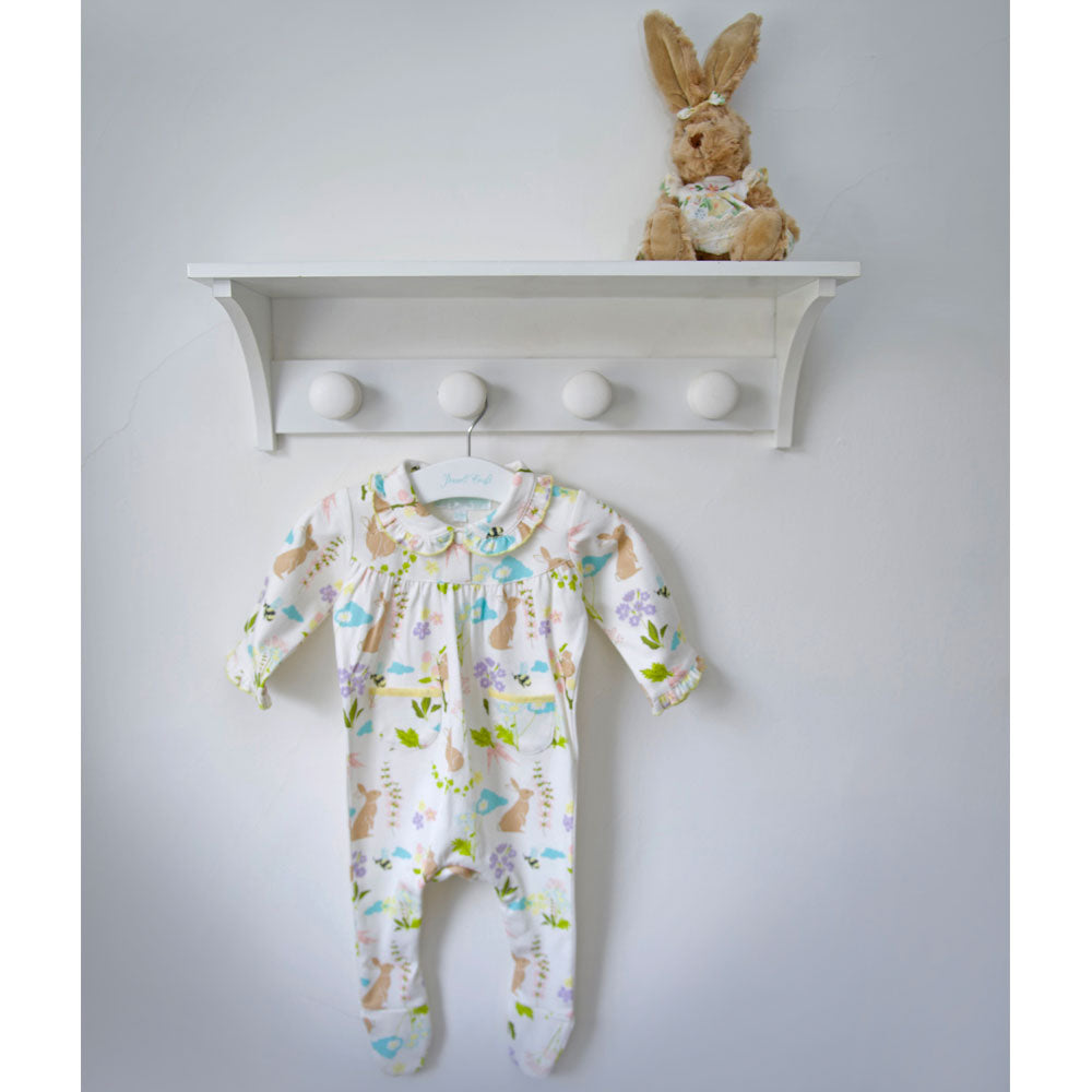 Meadow Print Jumpsuit hanging on a peg rack with a toy bunny