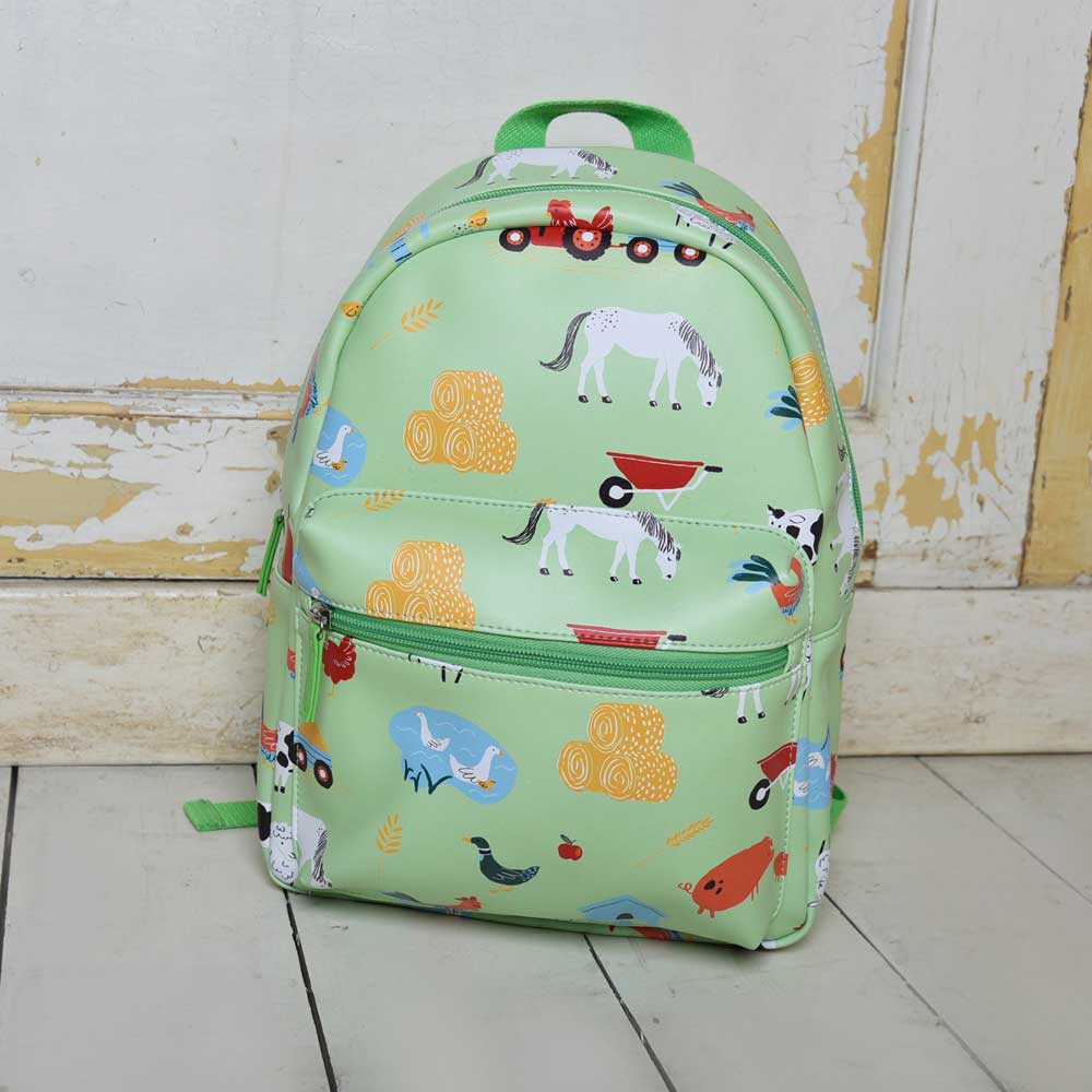 Farmyard Print Backpack styled against a white wooden wall