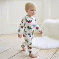 Baby toddler wearing white tractor print jumpsuit walking on wooden floor