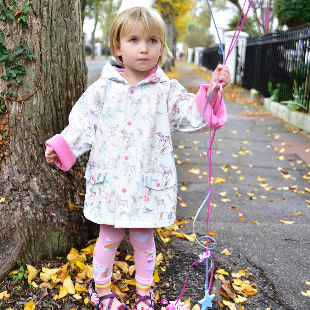 Young girl wearing the Unicorn Print Raincoat outdoors in autumn